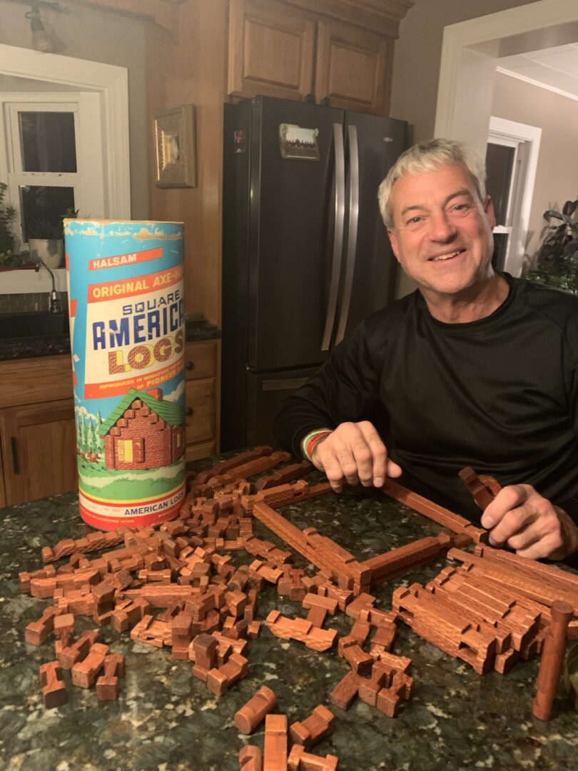 Man building with wooden logs.